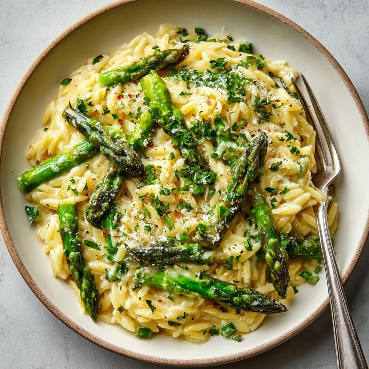 A steaming plate of Lemon Butter Orzo; bright green asparagus peeks through.