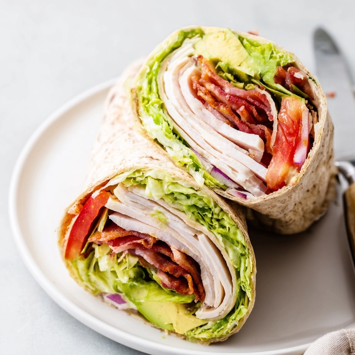Golden-brown Avocado and Turkey BLT Wraps, toasted and halved, served with a side salad.