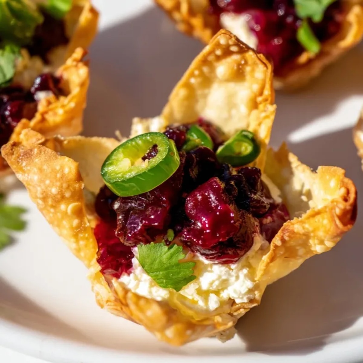 A bite-sized cranberry jalape&amp;ntilde;o dip wonton cup showing layers of sweet and spicy flavors.