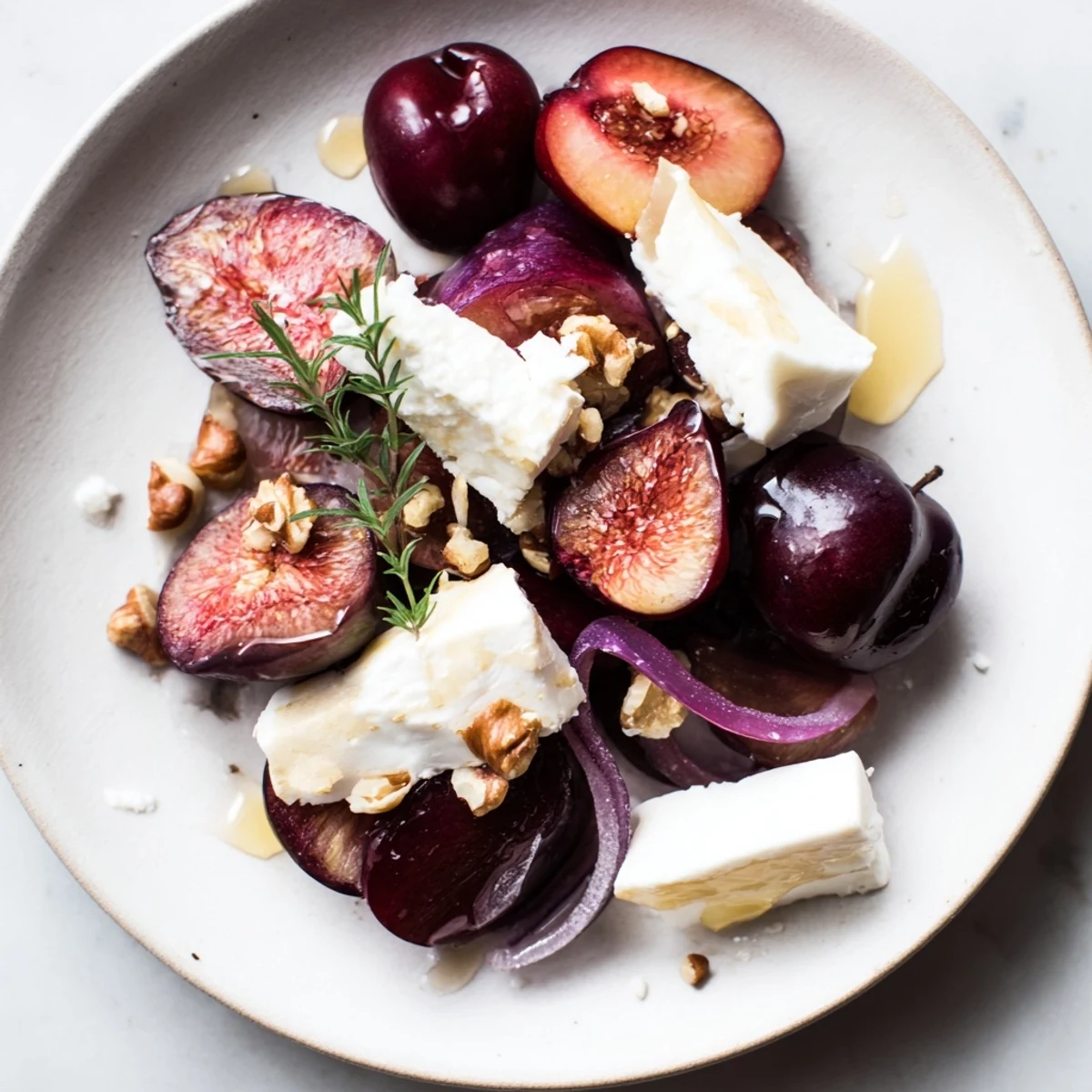 A Midnight Orchard appetizer arrangement: showcasing grapes, cheese, and plums, garnished with thyme sprigs and walnuts.