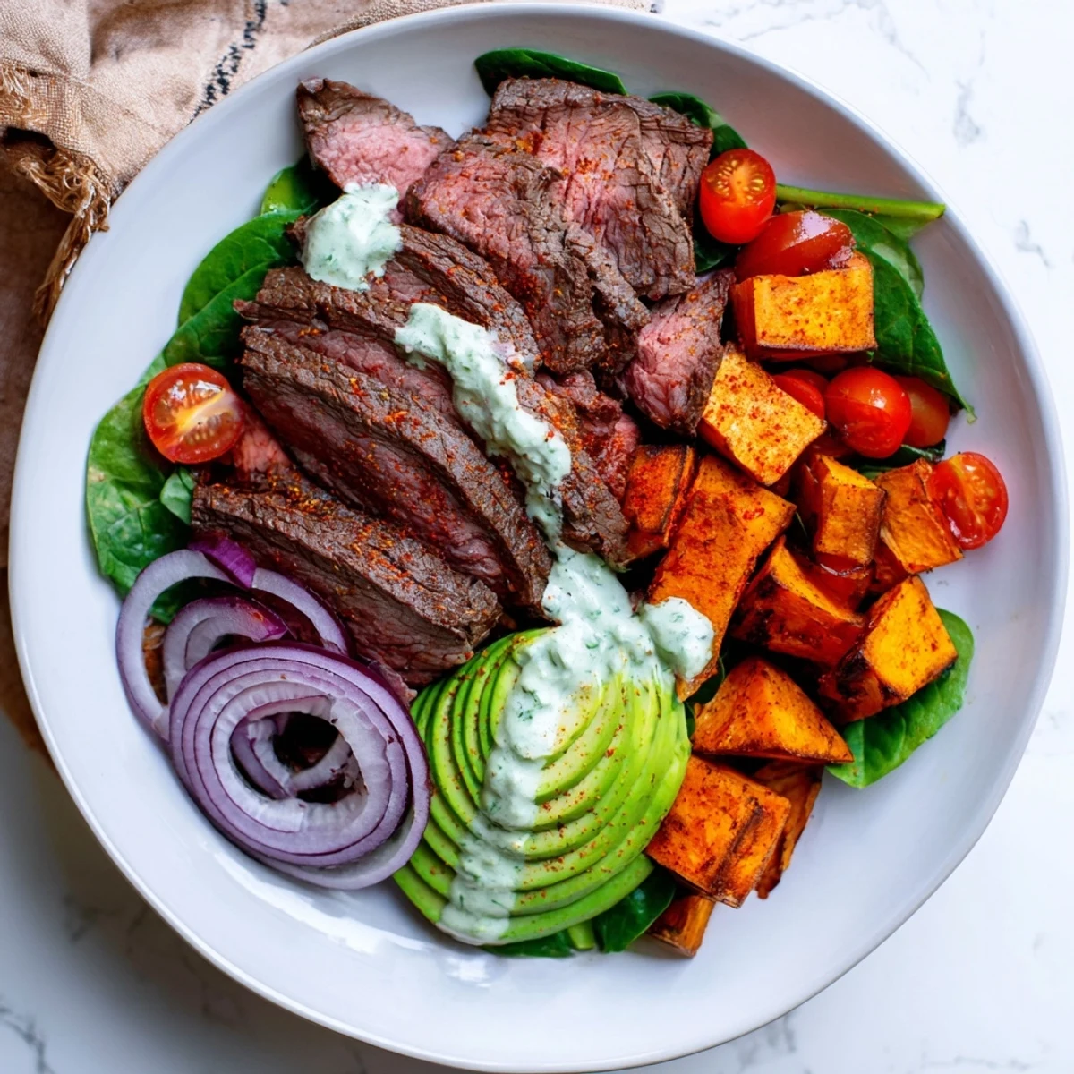 Savory Beef Avocado Sweet Potato Bowl, drizzled with lime yogurt dressing, offering a delightful mix of textures.