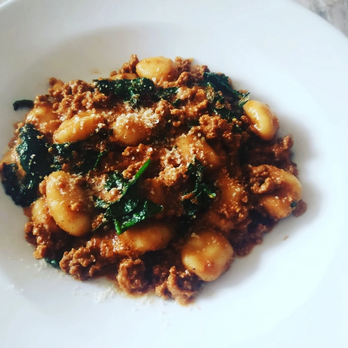 Hearty Italian-inspired sausage gnocchi tossed with wilted kale and diced tomatoes, served hot and steaming from the skillet.