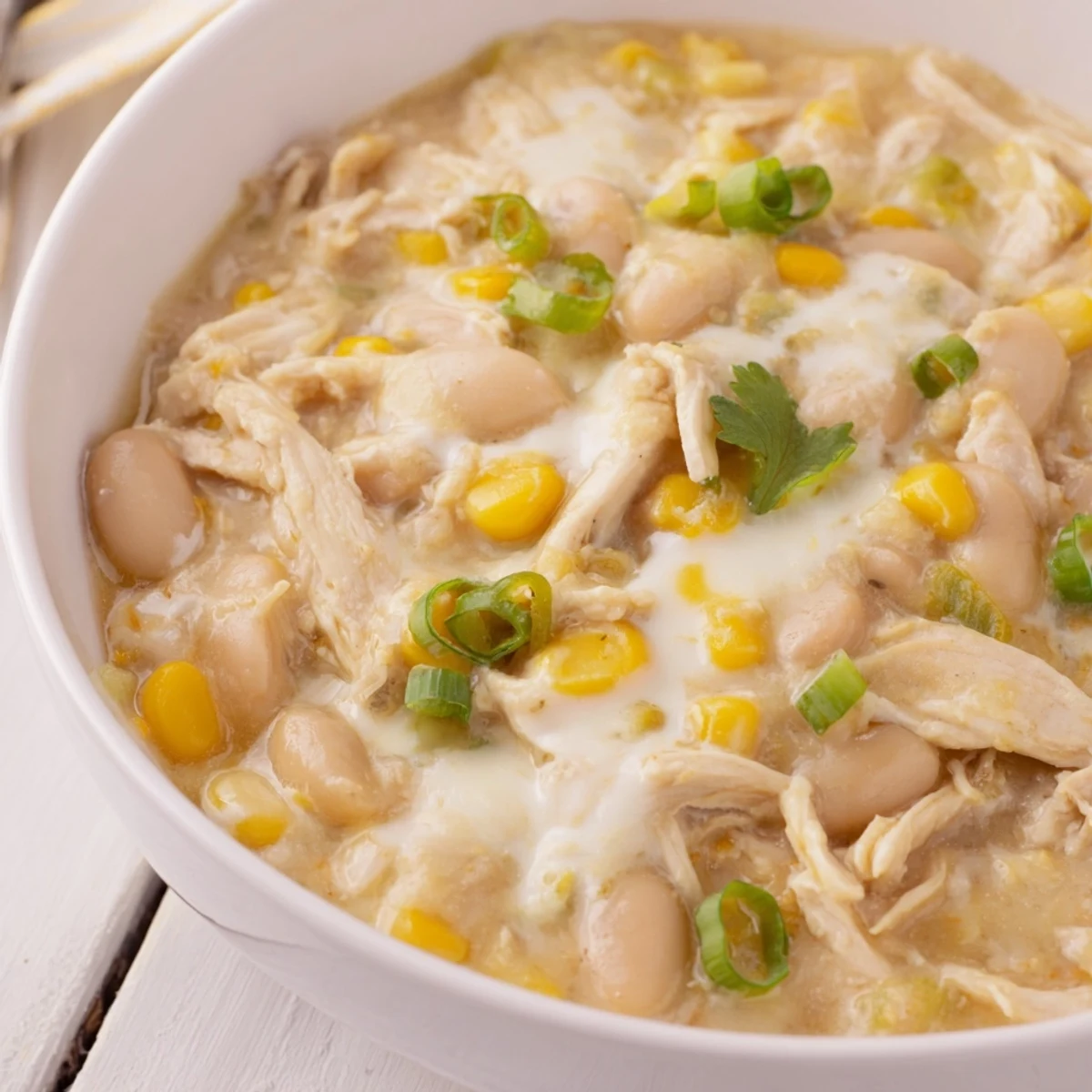 Steaming bowl of homemade White Chicken Chili topped with cilantro and melted cheese beside a lime wedge.  