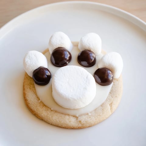 Perfectly decorated Polar Bear Paw Print Cookies with marshmallow toes and chocolate paw pads.