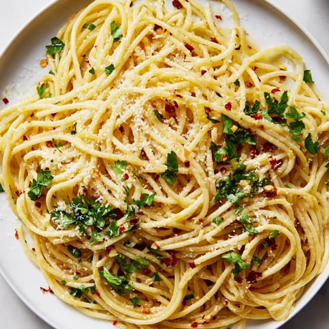 Steaming plate of Aglio e Olio express pasta, glistening with garlic-infused oil and fresh parsley garnish.