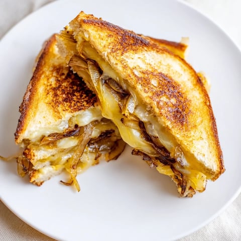 Golden, bubbly Caramelized Onion and Gruyère Grilled Cheese, oozing with melted Gruyère, ready to savor.