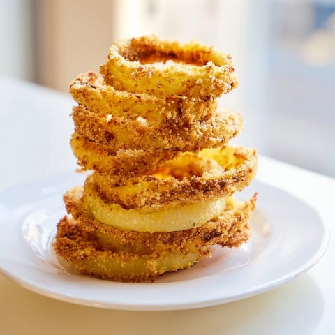 Golden, crispy Crispy Onion Ring Tower, stacked high, ready for dipping into creamy sauces.