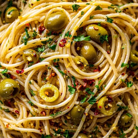 Spaghetti with green olives and red pepper flakes.