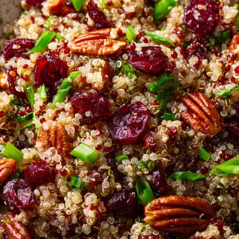 A bowl of food with rice, nuts, and berries.