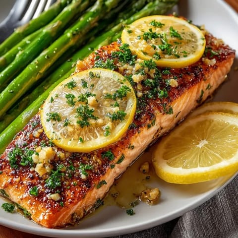 Juicy sheet pan lemon garlic salmon with asparagus, garnished with fresh lemon slices and herbs