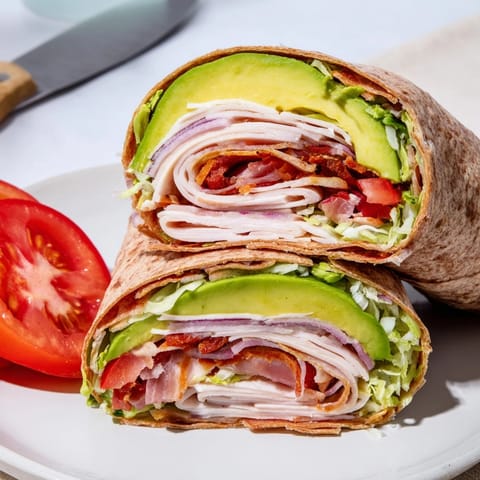 Making fresh Avocado and Turkey BLT Wraps, showing hands layering ingredients onto a tortilla.
