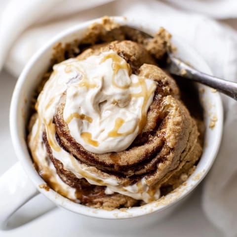 Easy Protein Cinnamon Roll Mug Cake: golden and steamy in a white mug.