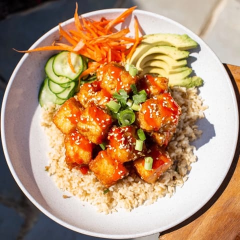 A delicious, close-up shot of chili-mayo baked tofu bowls, garnished with sesame seeds and cilantro.