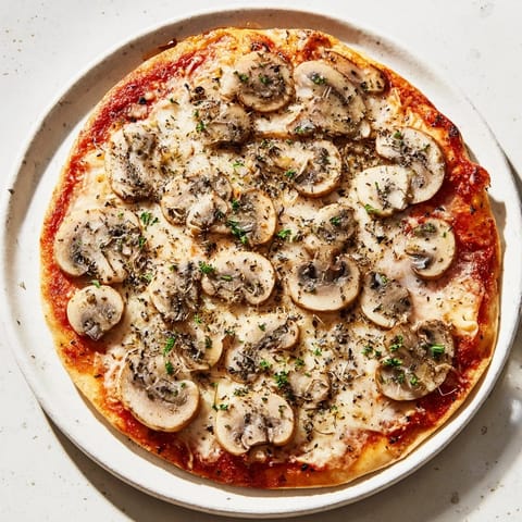 Melting mozzarella blankets a gourmet frozen pizza featuring mushrooms and fragrant, dried herbs.