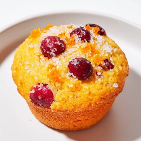A close-up of fluffy quick festive cranberry orange muffins overflowing with cranberries ready to eat.