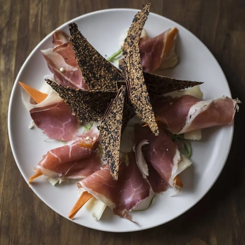 Vibrant overhead shot of the Paper Crane, showcasing the delicate folds of cured meats and creative cracker placement.