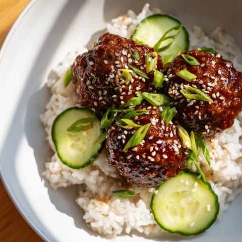 Savory teriyaki meatball bowls featuring tender meatballs coated in a sweet teriyaki glaze with fresh garnishes.