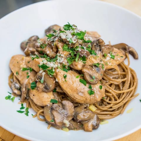 A visually appealing plate of creamy mushroom chicken spaghettini, garnished with fresh parsley and Parmesan cheese.
