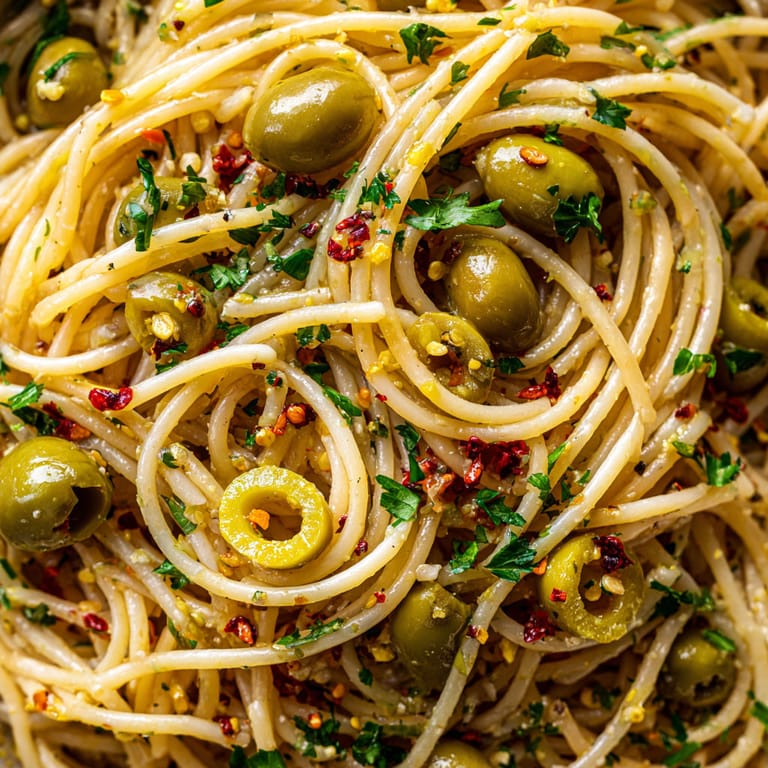 Spaghetti with green olives and red pepper flakes.