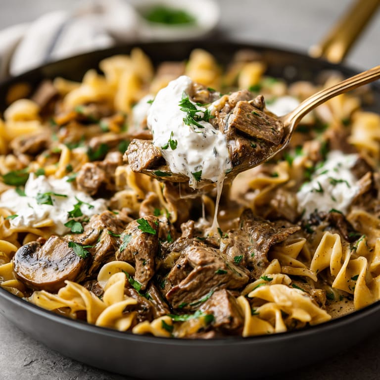 A bowl of pasta with meat and sauce.