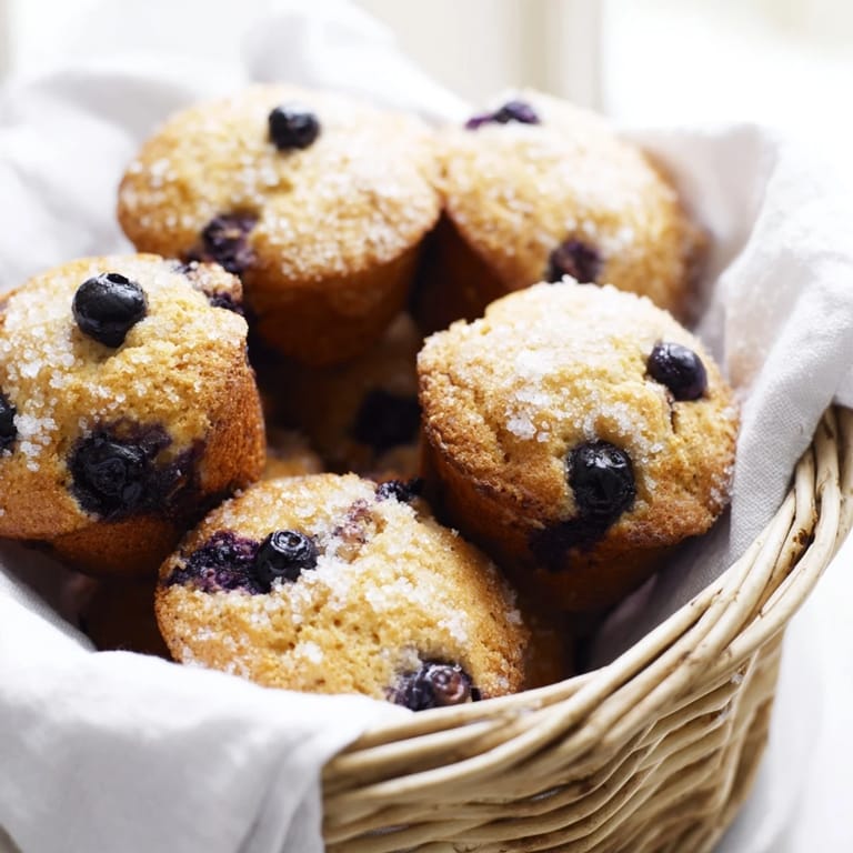 Warm, golden-brown mini blueberry muffins, fresh from the oven, perfect for brunch.