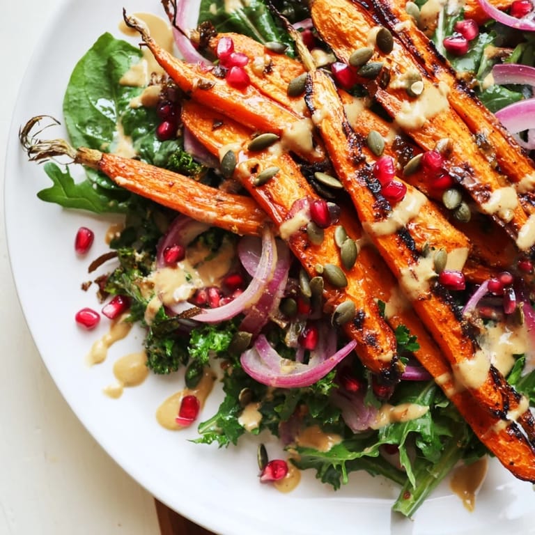 Brightly plated roasted carrot salad, featuring caramelized carrots drizzled with creamy tahini dressing.