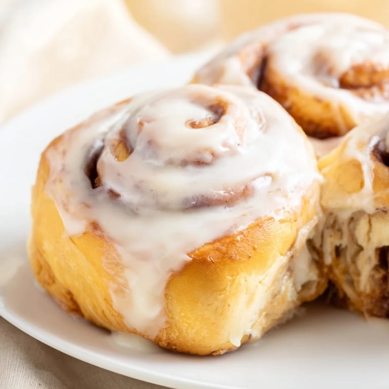 A close-up of golden brown Pillow Soft Cinnamon Rolls, demonstrating their soft, pillowy texture and delicious filling.