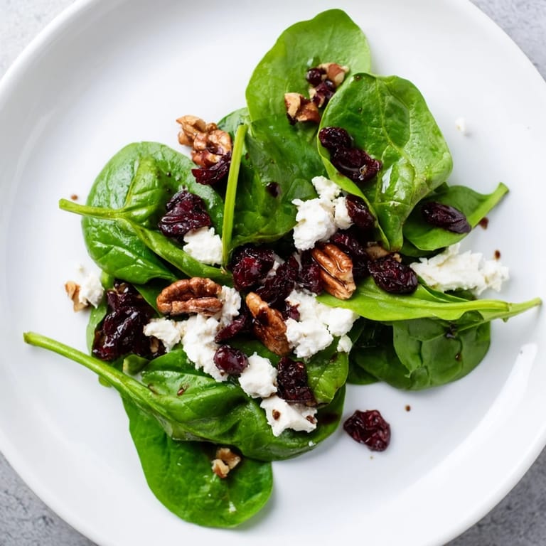 This colorful spinach goat cheese salad displays a beautiful arrangement of ingredients, ready to eat and enjoy.