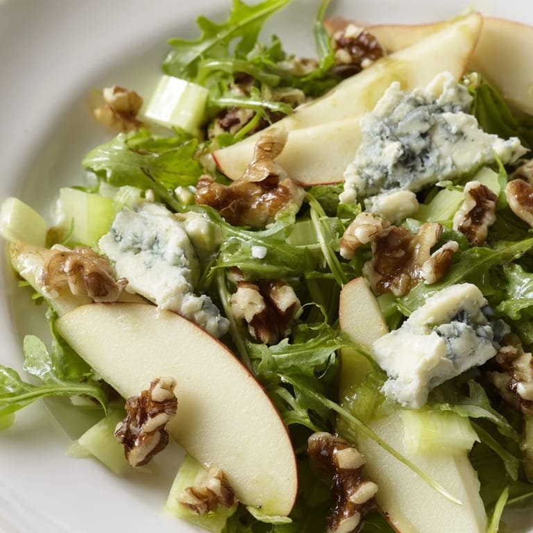 Freshly tossed Apple and Walnut Salad with toasted walnuts and greens, glistening with apple cider vinaigrette on a rustic plate.