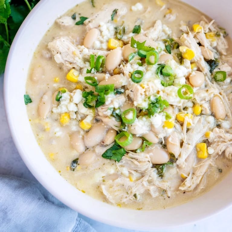 Spicy White Chicken Chili served in a rustic bowl with green onions and Monterey Jack cheese.