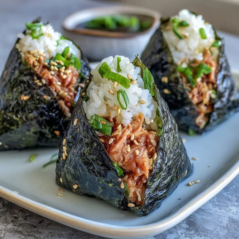 Delicious onigiri stuffed with creamy, spicy tuna and wrapped in nori, perfect for a portable Japanese-inspired lunch.
