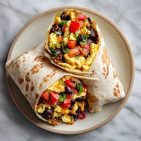 Two burritos filled with eggs and vegetables.